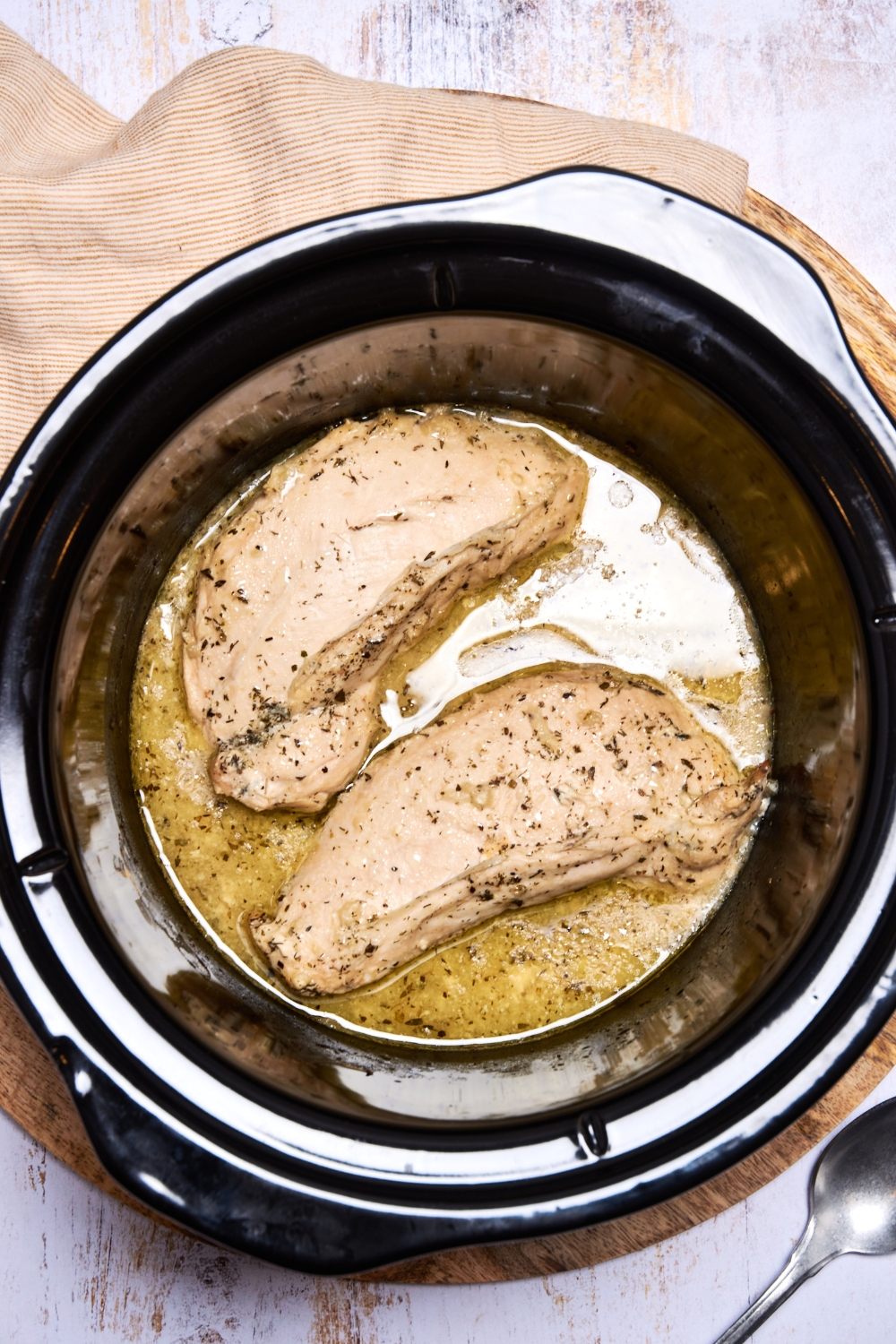 A crockpot with cooked turkey breast in a melty butter sauce.
