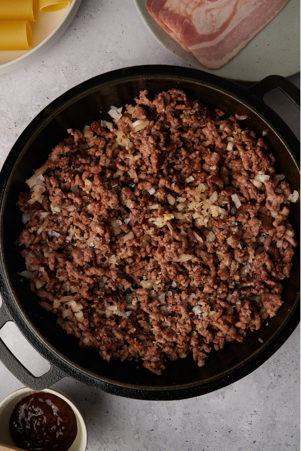 A skillet with ground beef cooking with garlic, onions, and seasonings mixed in.