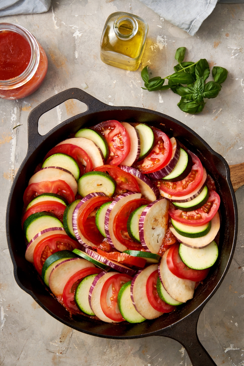 A cast iron pan is full of sliced vegetables ready to be cooked.