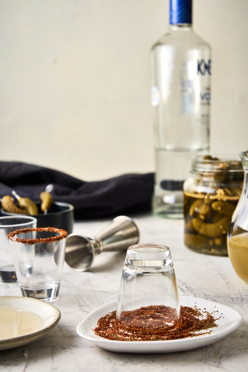 A plate with tajin seasoning and the shot glass being rimmed with it.