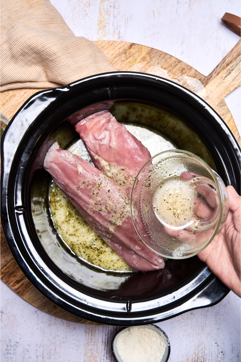 Butter sauce being poured over the frozen turkey in the crockpot.