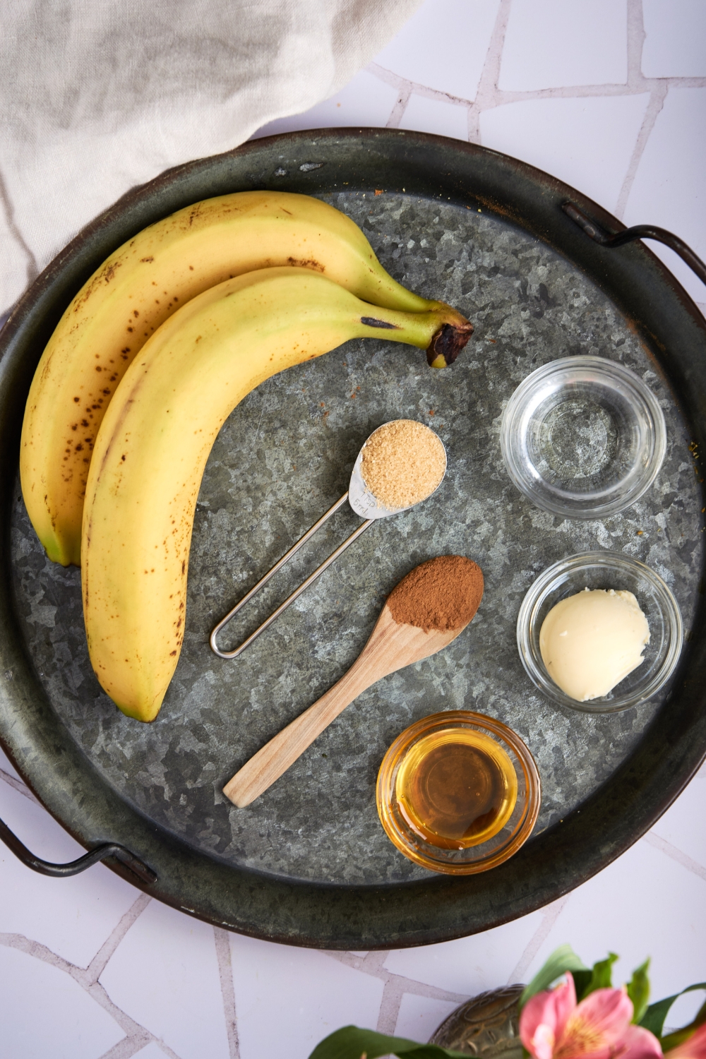 A serving tray with bananas, honey, butter, water, cinnamon, and brown sugar.