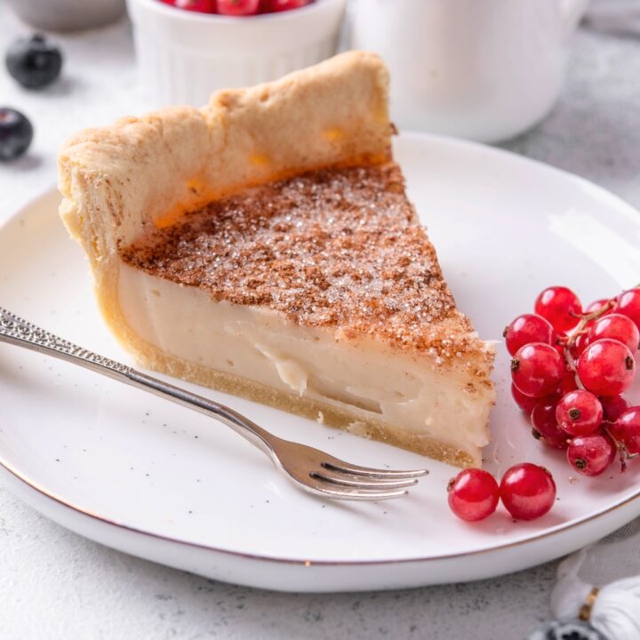 A slice of sugar cream pie on a white plate with a fork.