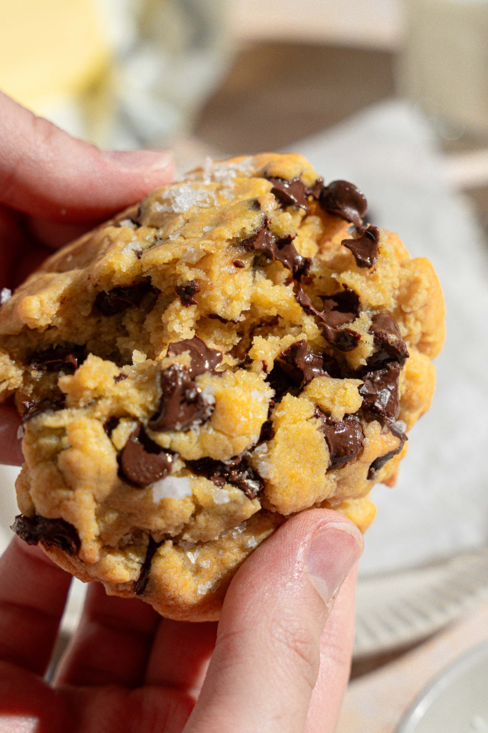 Two hands breaking apart a chocolate chip cookie.