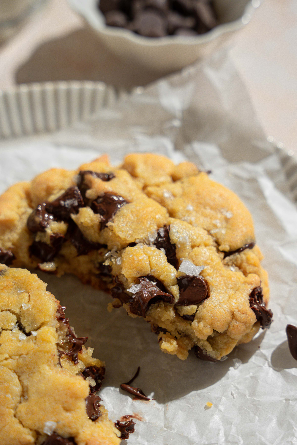 One half of a chocolate chip cookie on a piece of parchment paper.