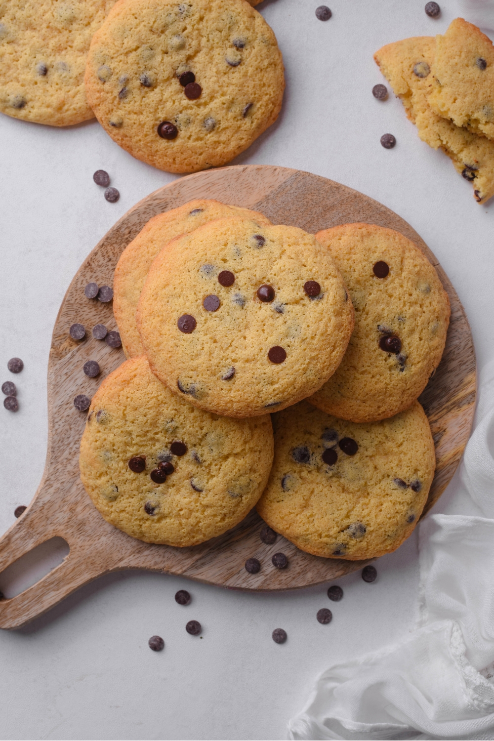A wooden serving board with golden brown chocolate chip cookies.