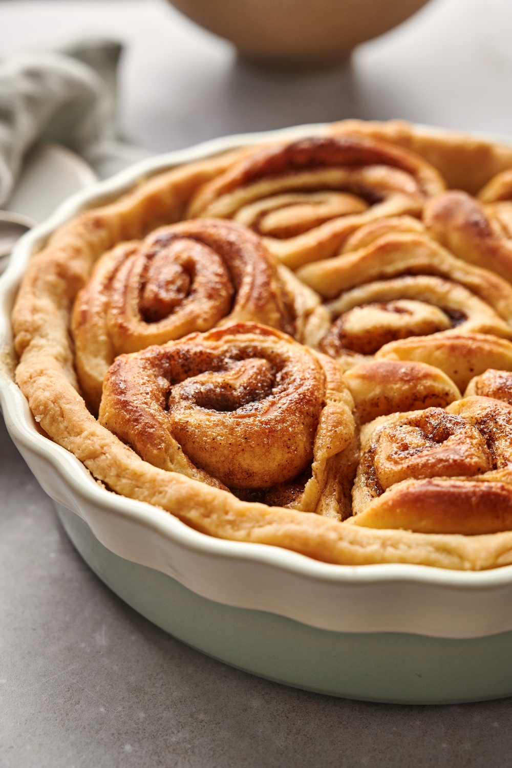 A pie dish with baked cinnamon roll peach cobbler.