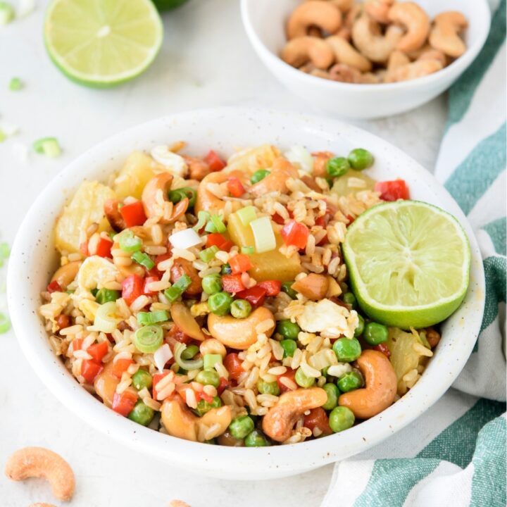 A bowl with pineapple rice and a halved lime.