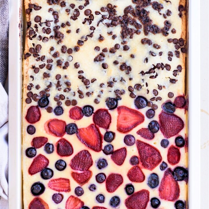 Pancakes in a sheet pan with chocolate chips on the top half and strawberries and blueberries on the bottom half.