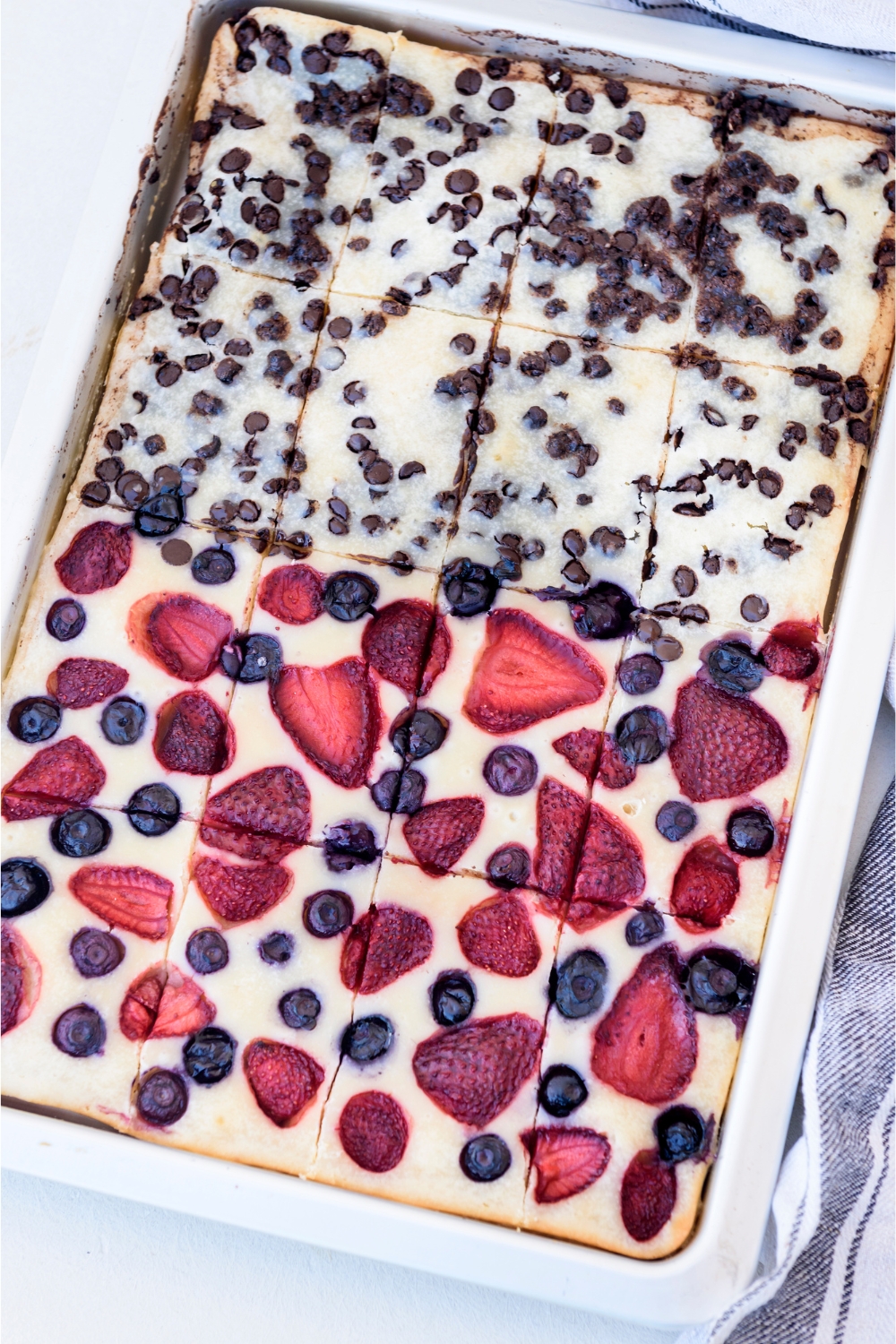 A baking sheet with sliced pancakes topped with chocolate chips, strawberries, and blueberries.