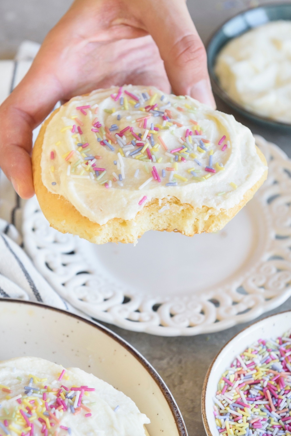 A sugar cookie with frosting with a bite out of it.