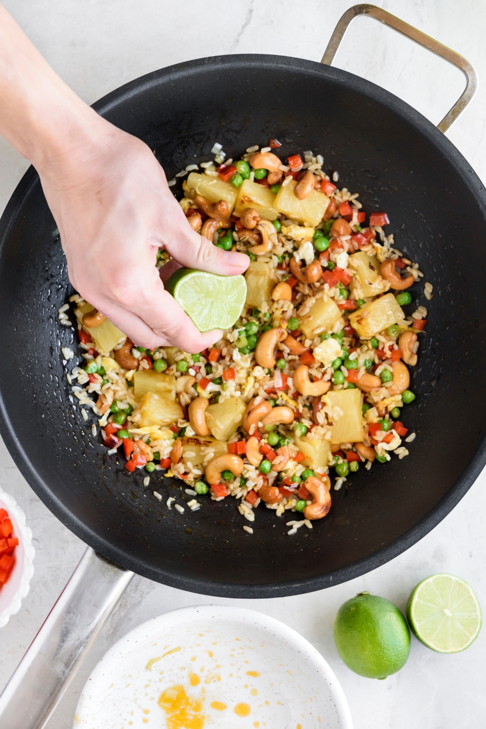 A skillet with lime juice being added to pineapple fried rice.