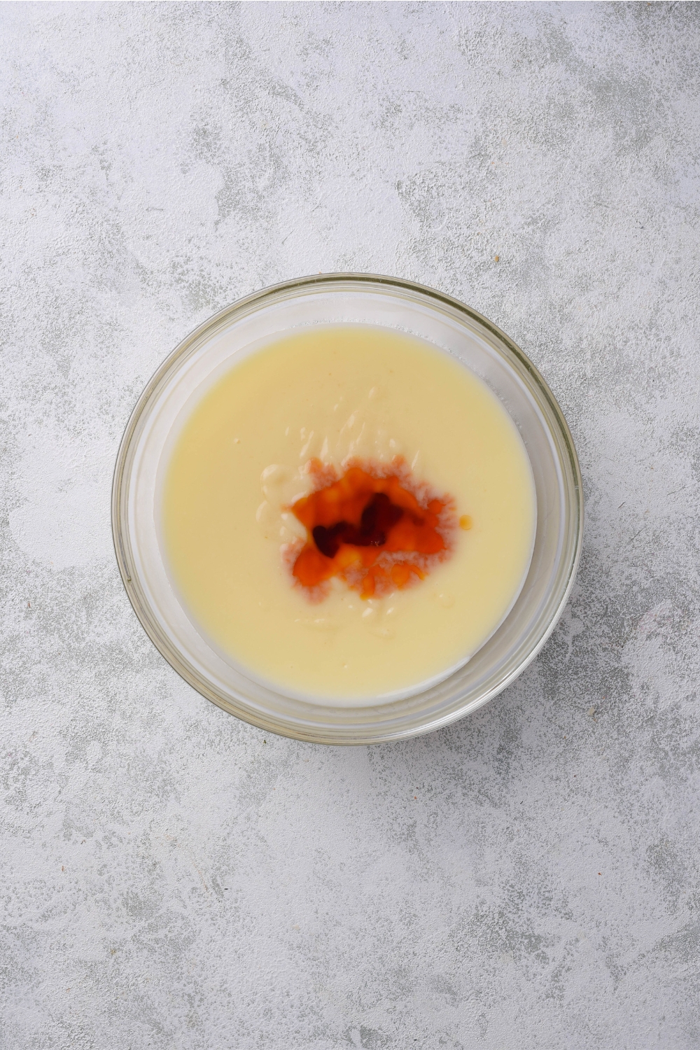 A mixing bowl with custard filling with vanilla added to it.