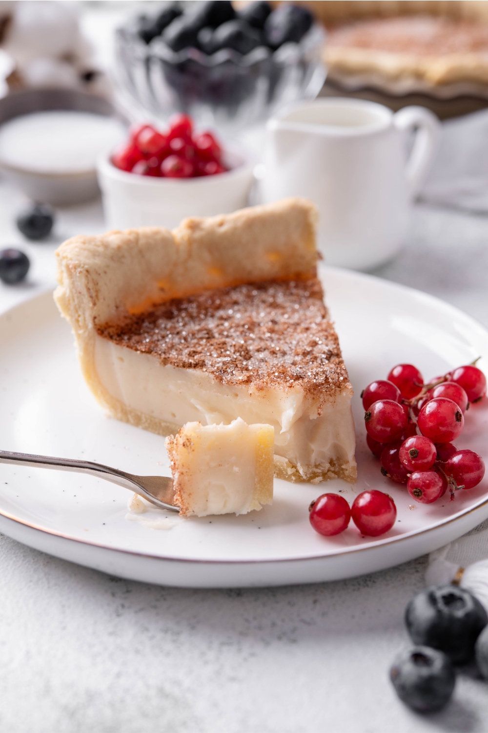 A small plate with a slice of sugar cream pie with grapes on the side.