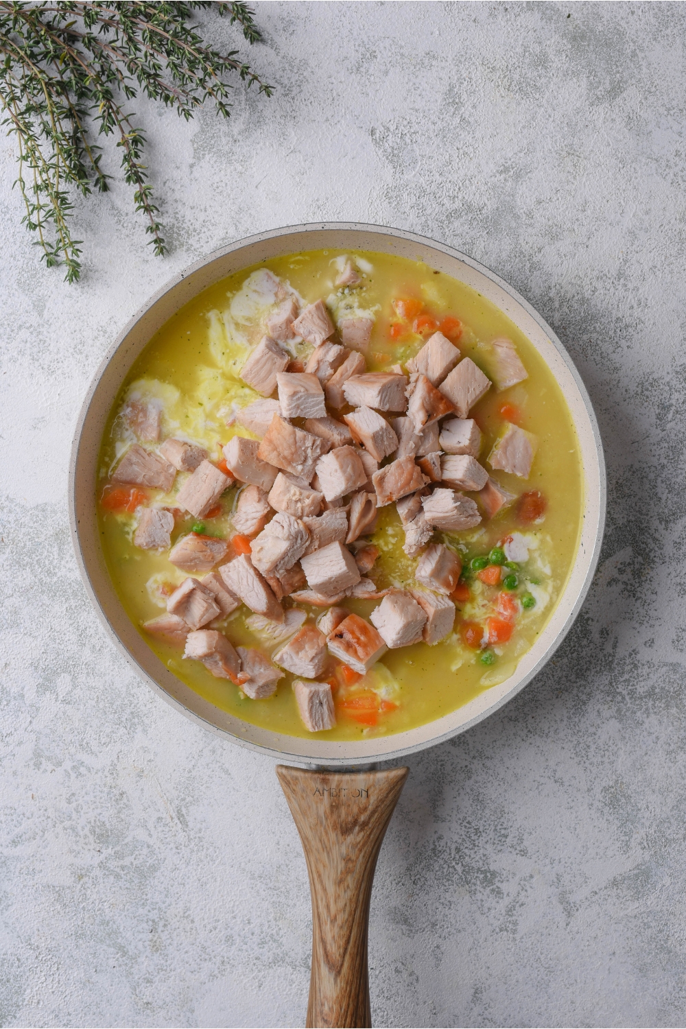 Chopped turkey on top of a broth mixture in a skillet on a grey counter.