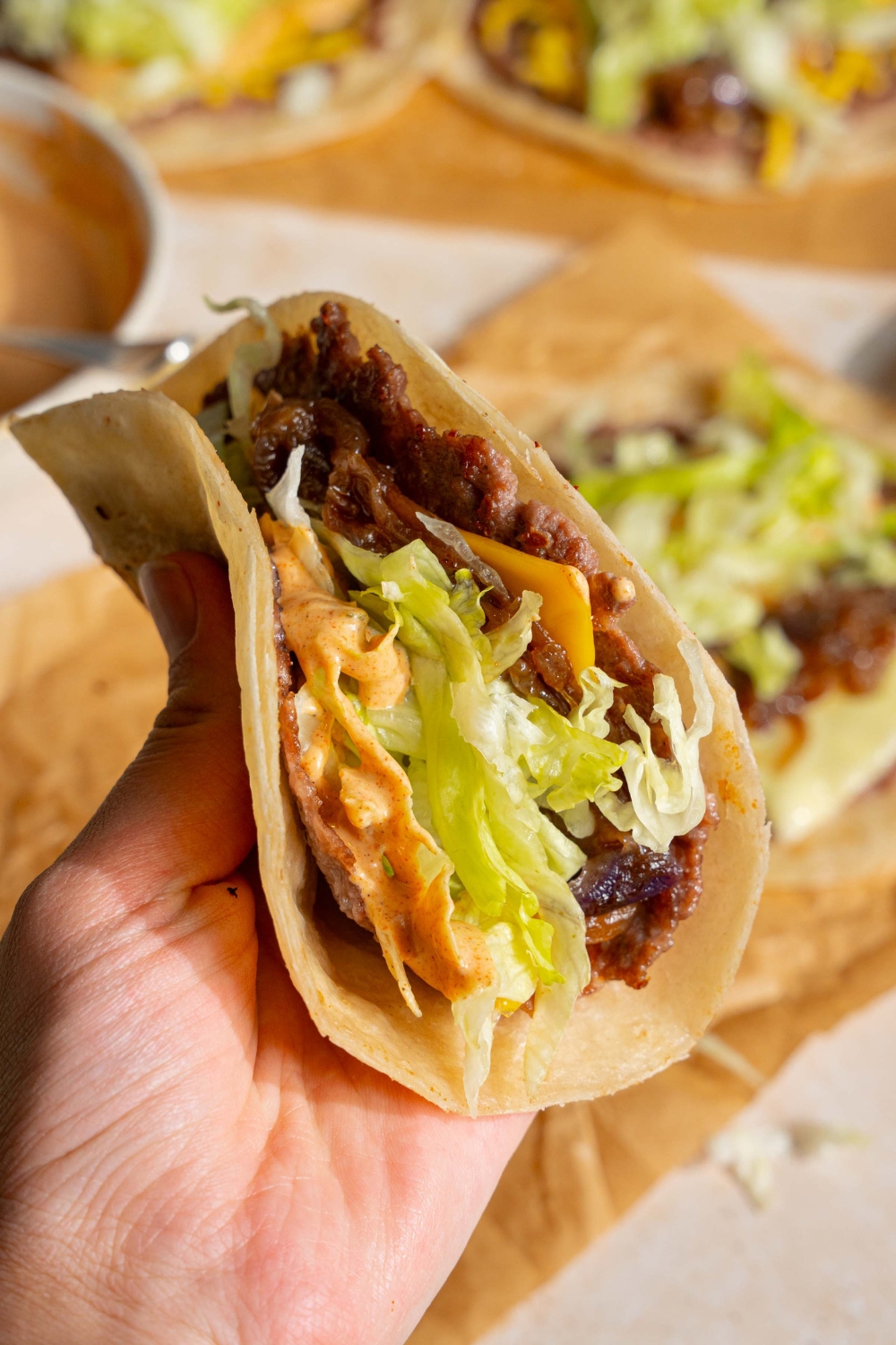 A hand holding a folded smash burger taco.