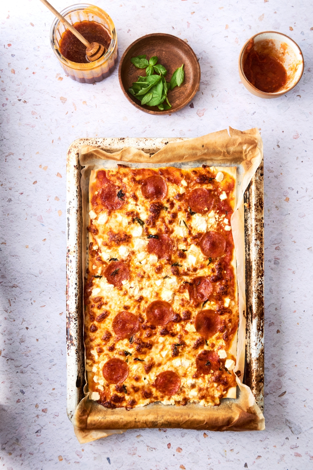 A baked pizza is on a parchment paper lined baking sheet.