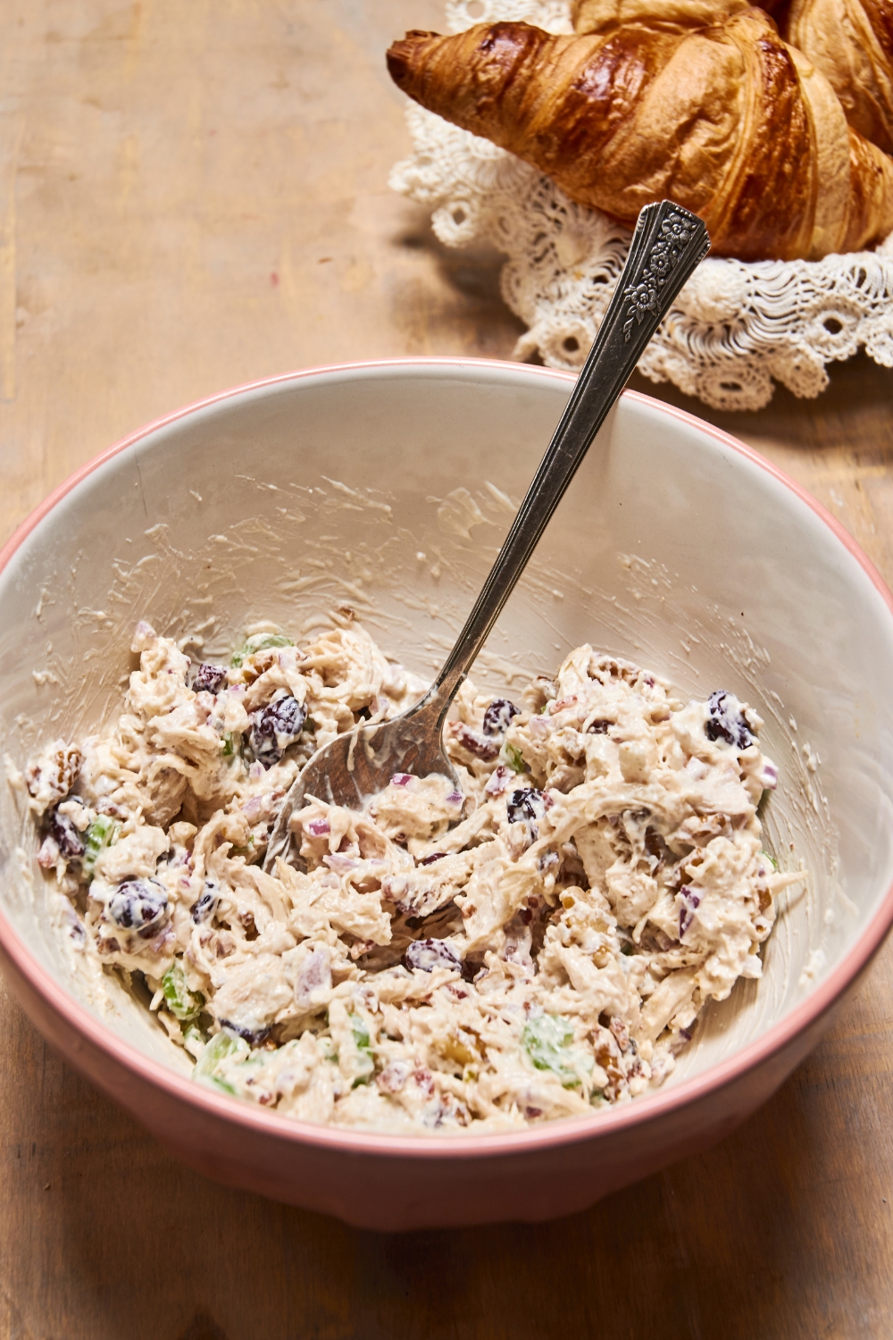 A gray bowl is full of chicken salad filling. A spoon is in the bowl as well.