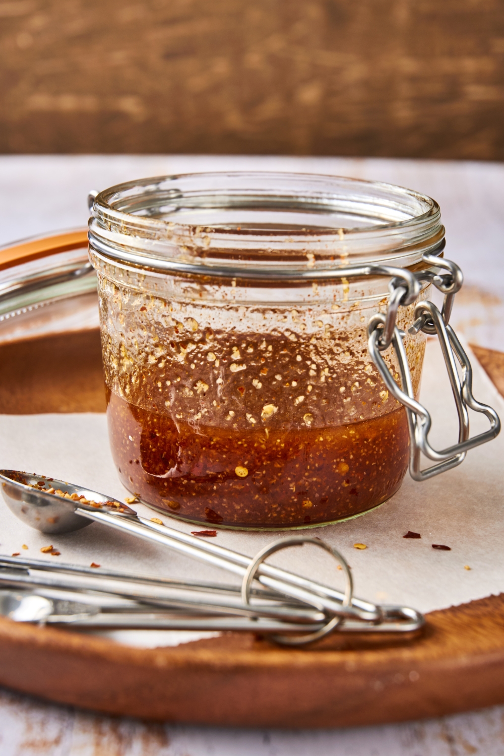 A glass jar of Popeye's sweet heat sauce sits on a tray with a set of measuring spoons.