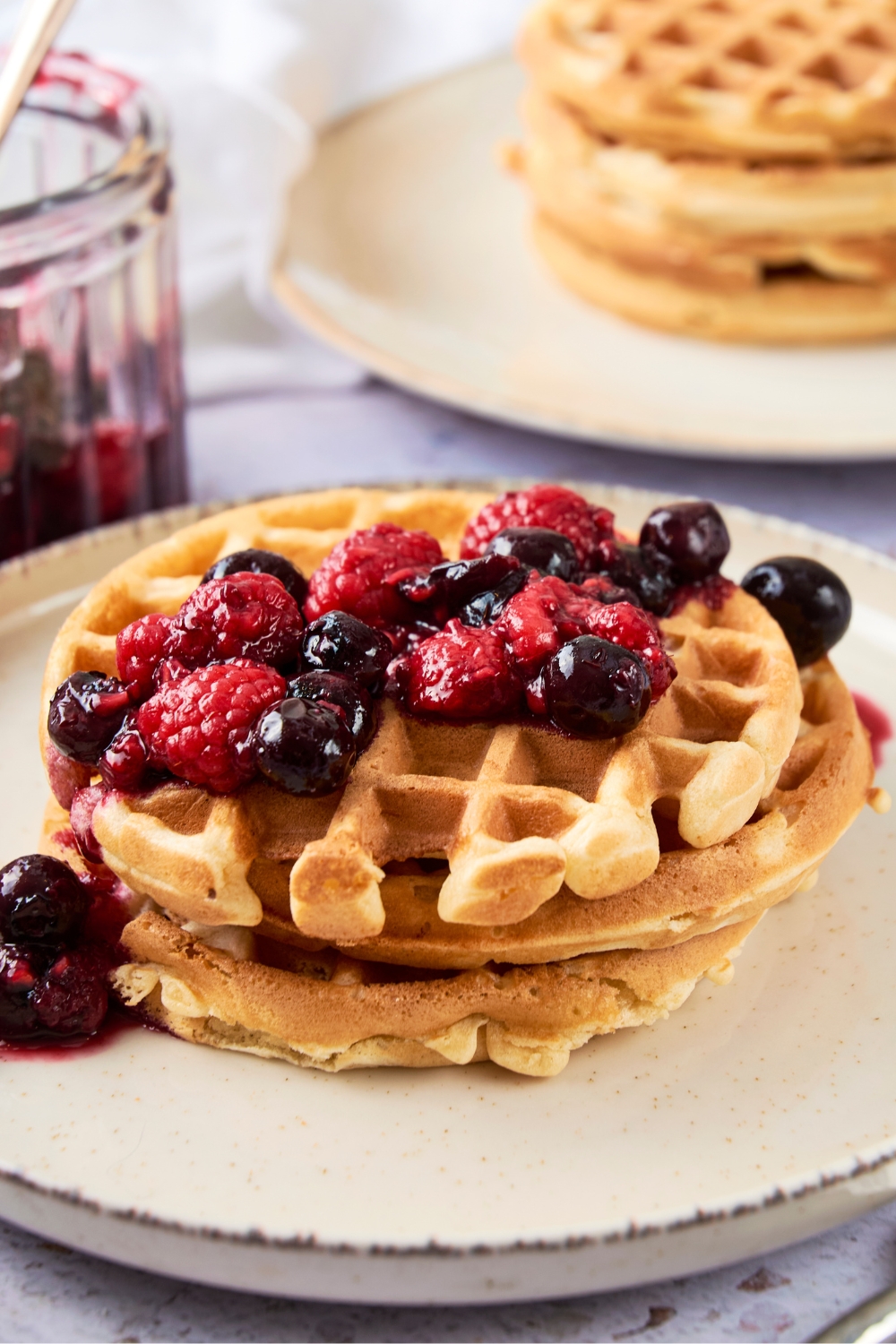 A stack of waffle house waffles sits on a plate. The waffles are topped with fresh berries.
