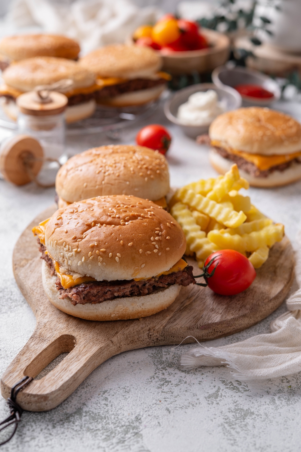 Two white castle sliders and french fries sit on a wooden serving board.