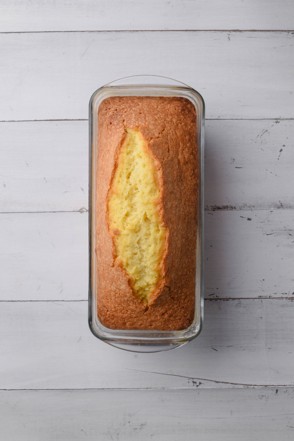 A golden brown old fashioned pound cake is in a glass loaf pan.