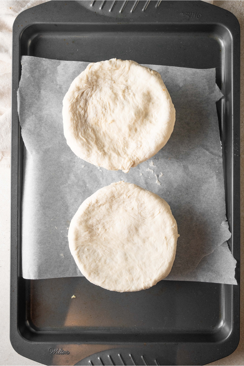 Two Chicago pizza pot pies are on a baking sheet. They are ready to go into the oven.