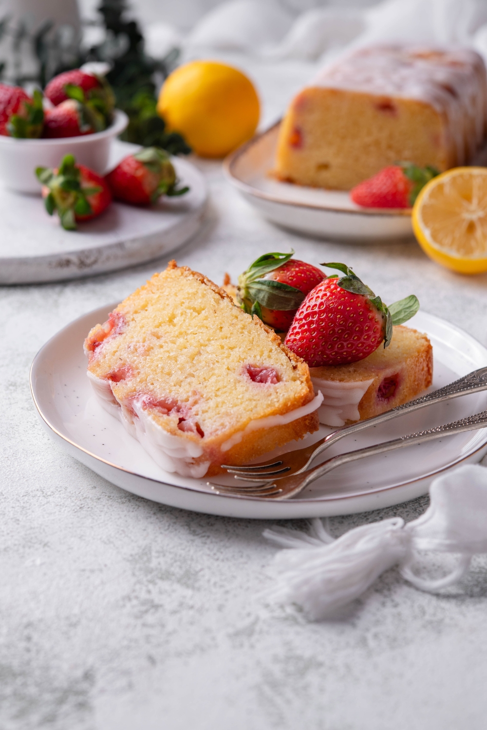 Two slices of strawberry pound cake are on a white plate. There are two forks resting on the plate.