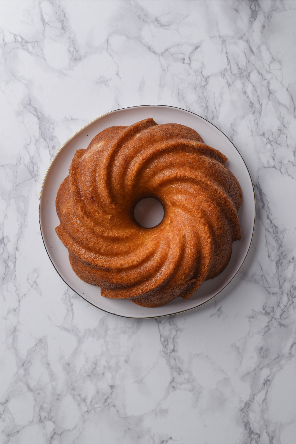 A baked and cooled buttermilk pound cake is on a white serving plate.