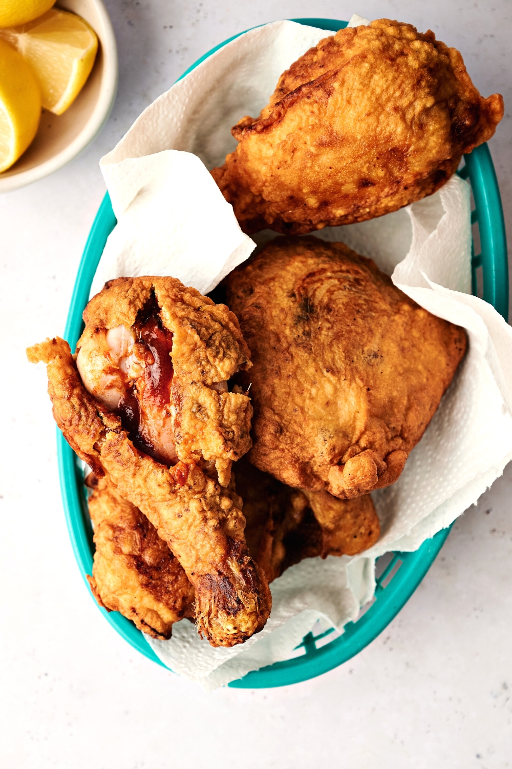 A fried chicken leg with sauce on top of more fried chicken.