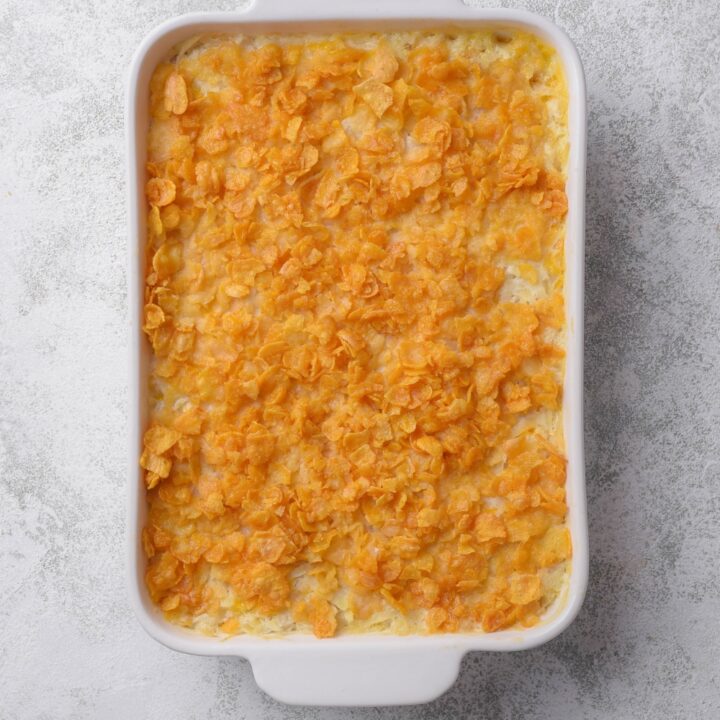 A casserole dish with baked hash brown casserole topped with corn flakes.