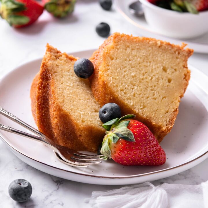 Two slices of buttermilk pound cake on a white plate with a strawberry.