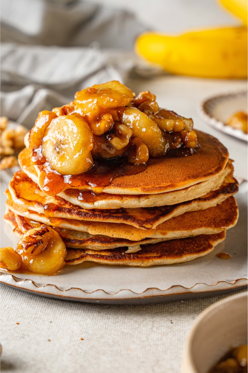 A stack of bananas foster pancakes topped with caramelized banana slices.