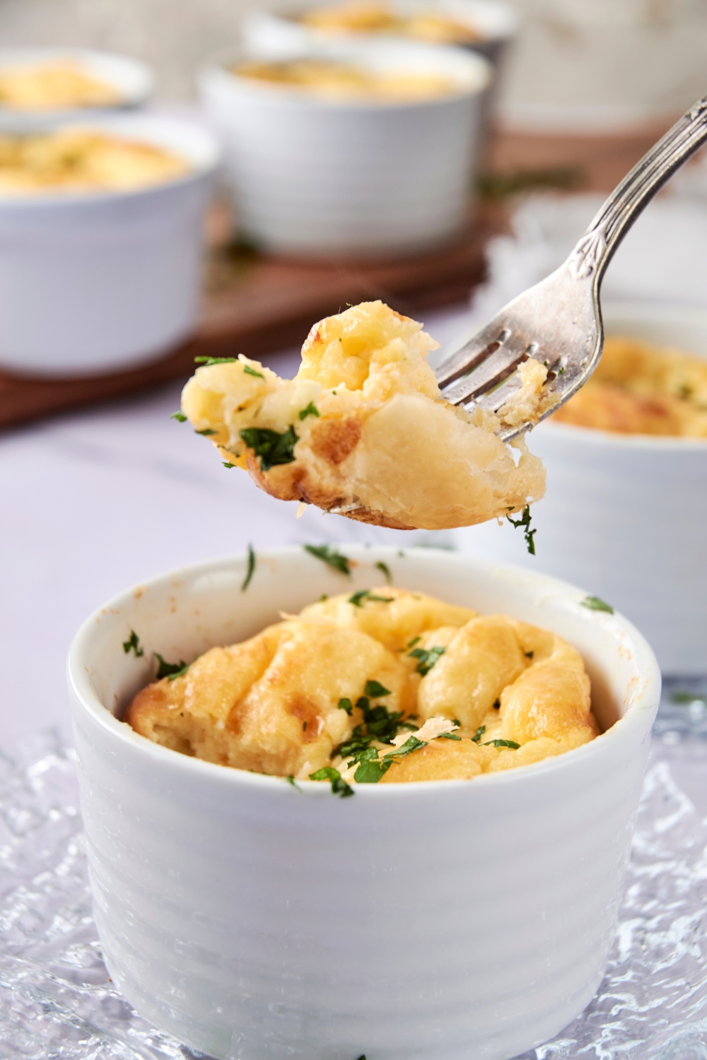 Someone lifts a bite of souffle out of a ramekin with a fork.