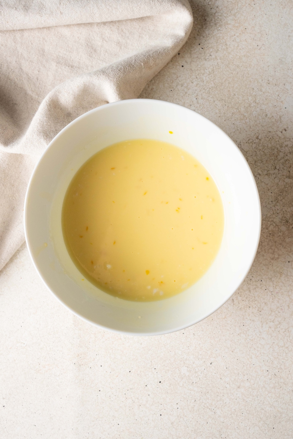 A white bowl holds coconut topping for the cassava cake.