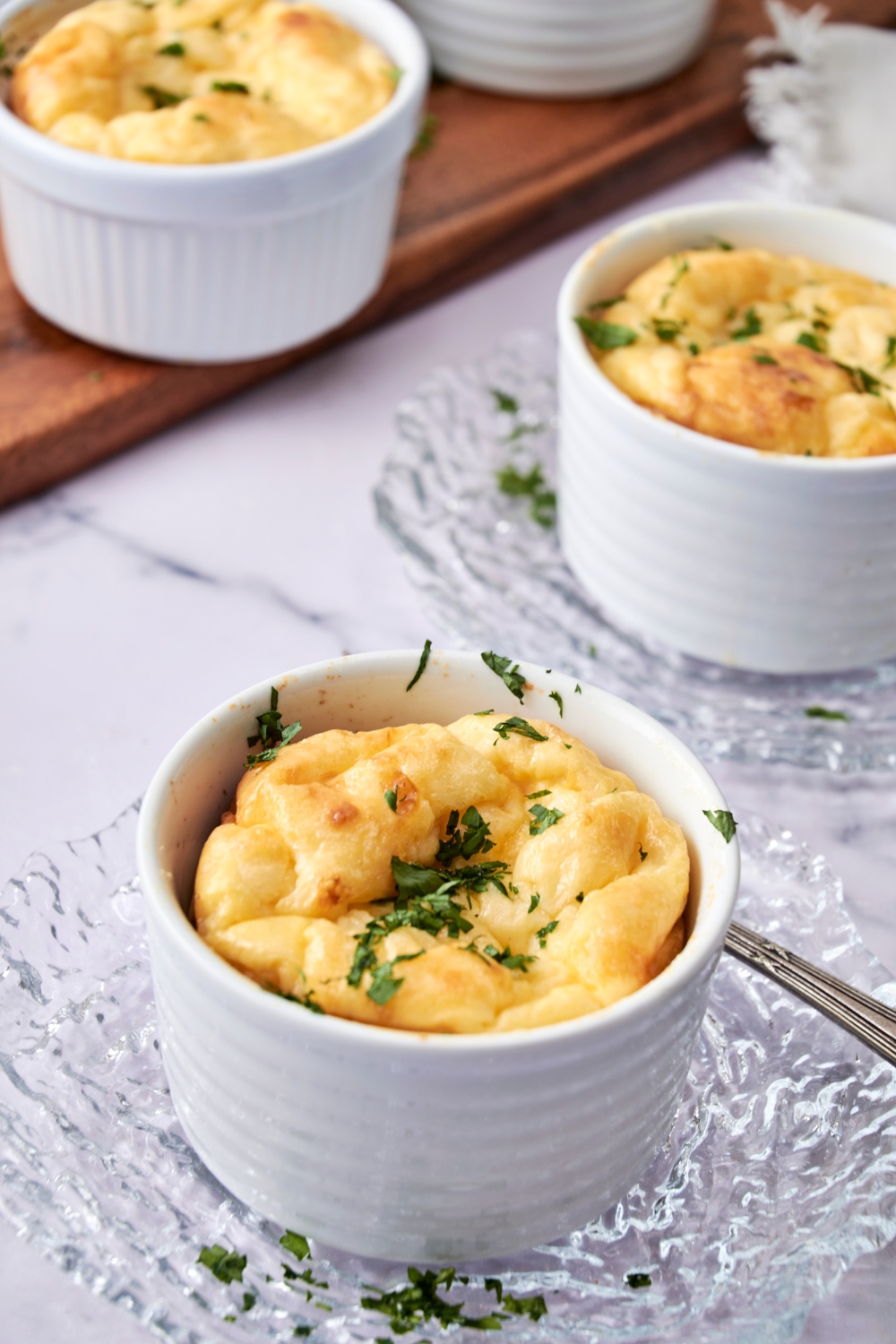 Three Panera souffles in white ramekins sit on glass plates waiting to be enjoyed.