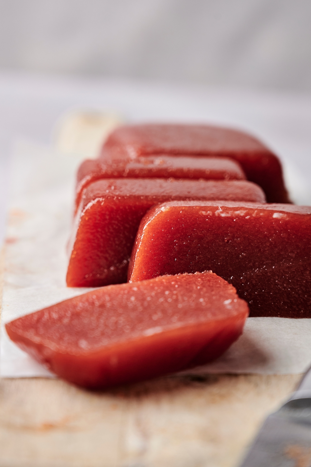 Slices of guava paste are on a wooden serving board.