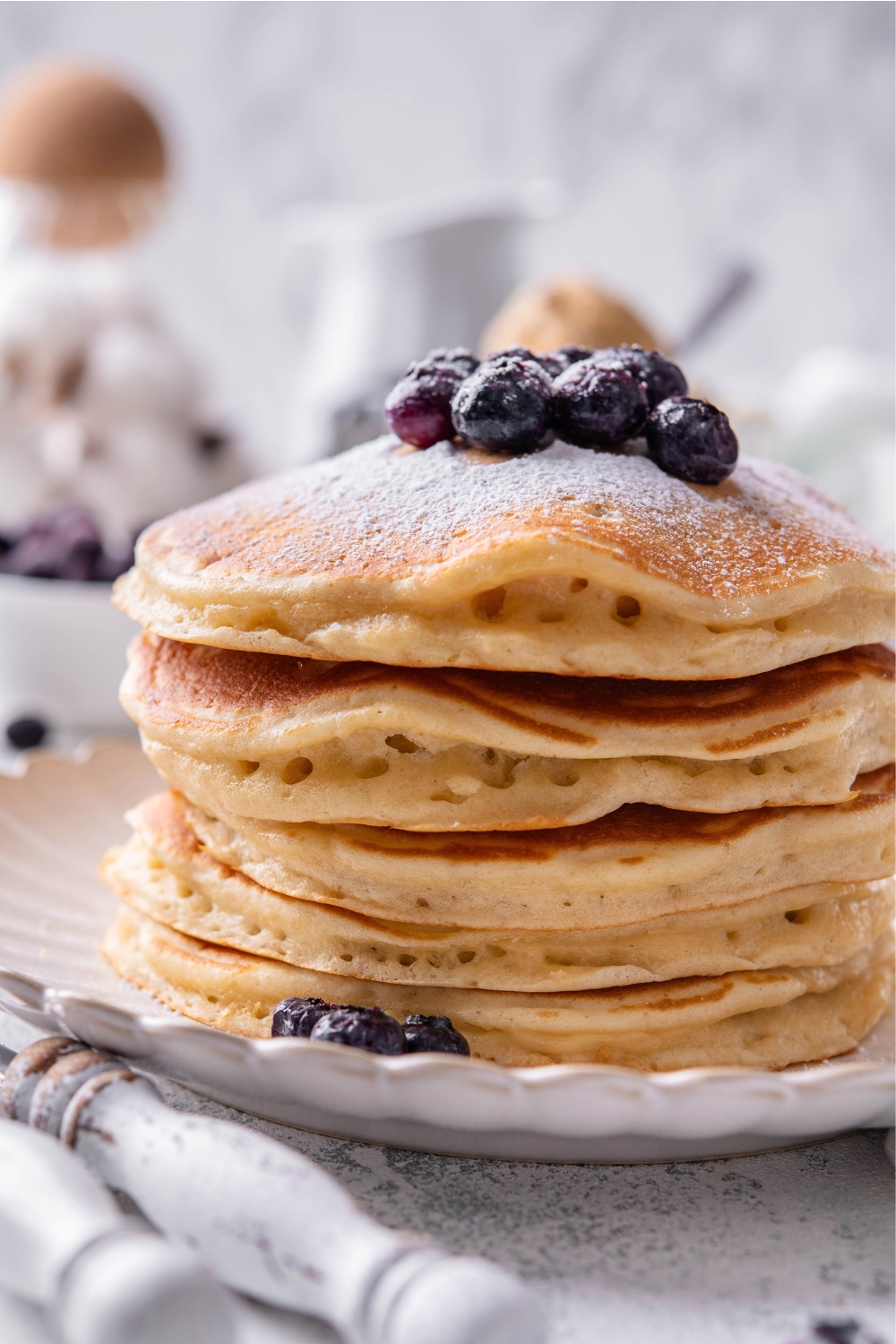 A stack of six buttermilk pancakes on a white plate.