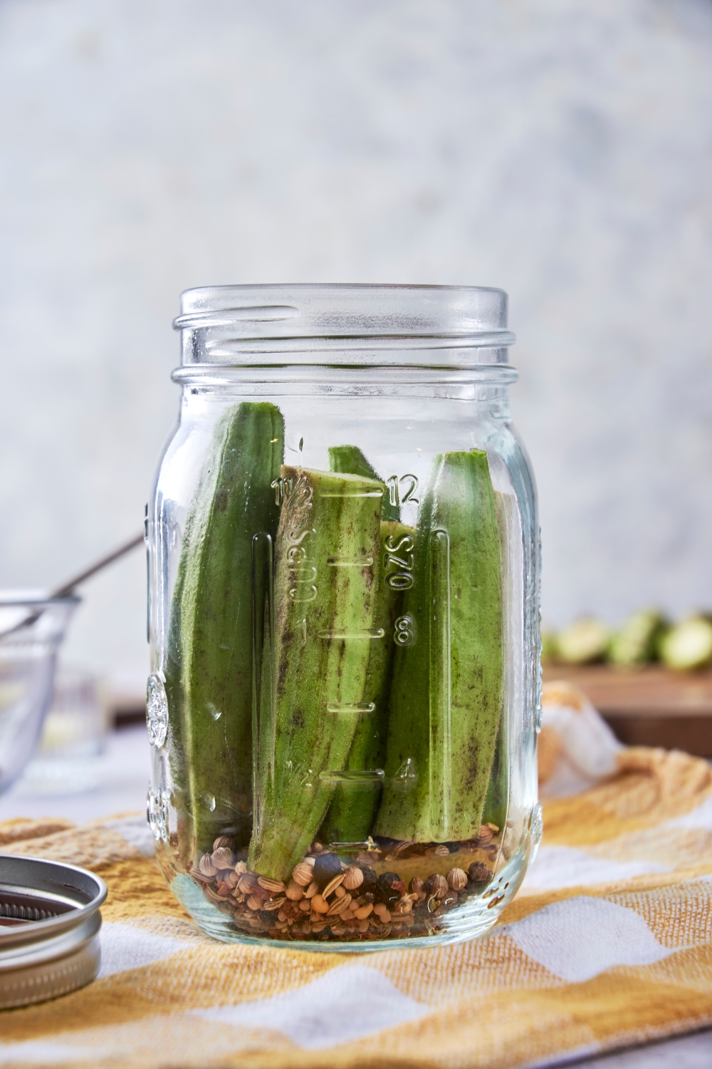 A jar with cut okra and pickling spices.