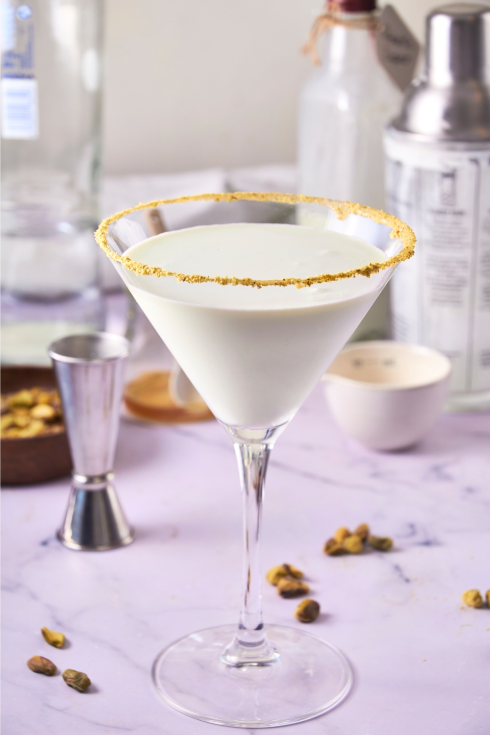 A martini glassed rimmed with crushed pistachios and filled with pistachio martini.