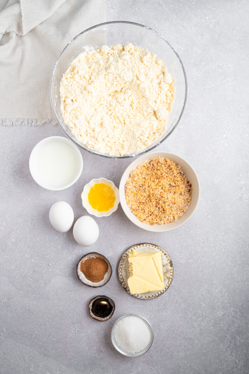 An overhead shot of several bowls in various sizes containing ingredients to make Bisquick coffee cake including Bisquick mix, sugar, milk, eggs, vanilla, cinnamon, butter, and brown sugar.