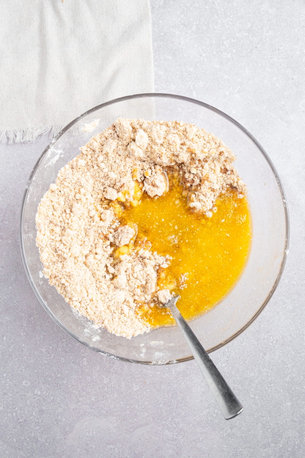 A glass bowl with ingredients to make a coffee cake crumb topping including brown sugar, Bisquick mix, cinnamon, and melted butter.