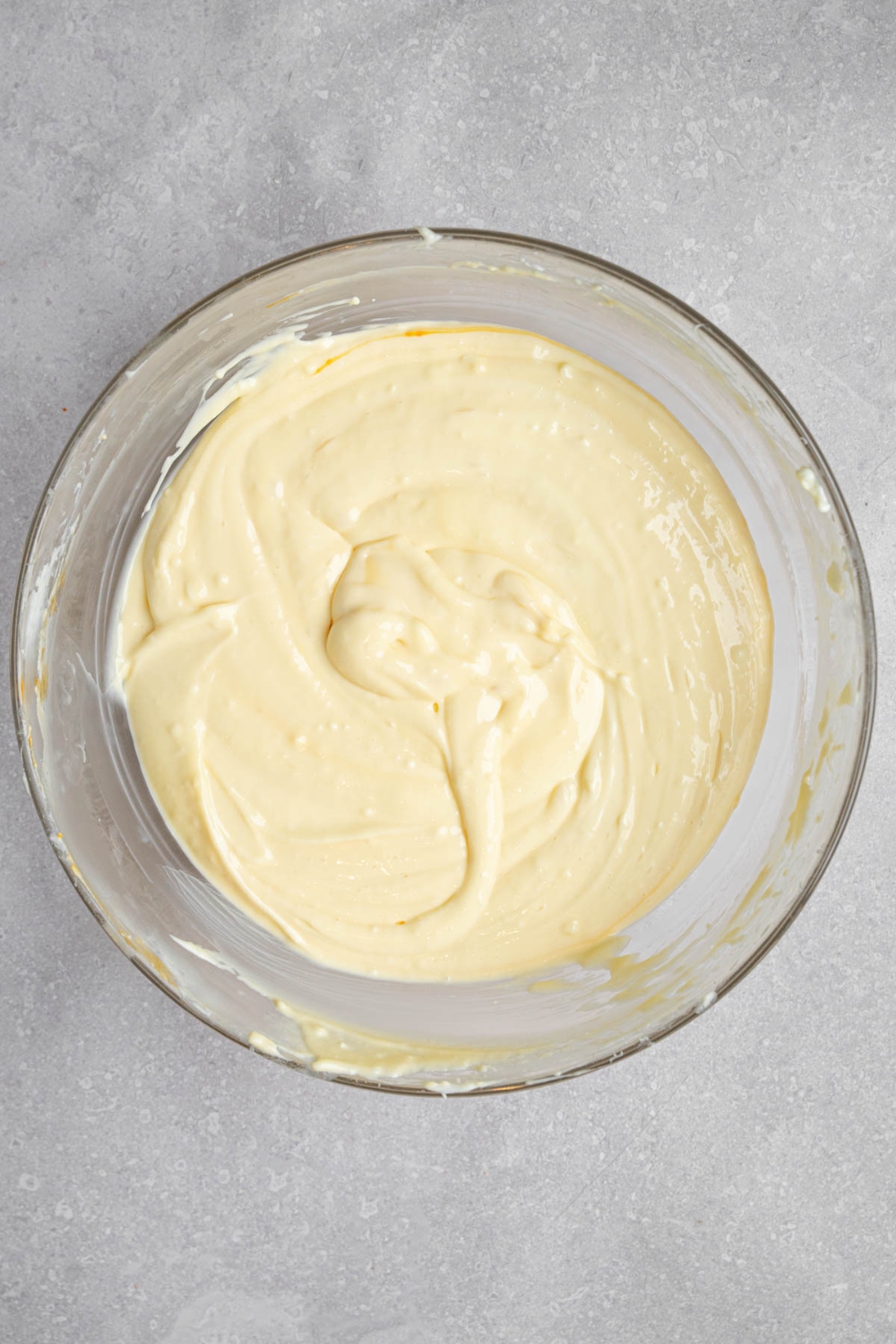 A glass bowl with a creme brulee cheesecake mixture. The bowl is on a white counter.