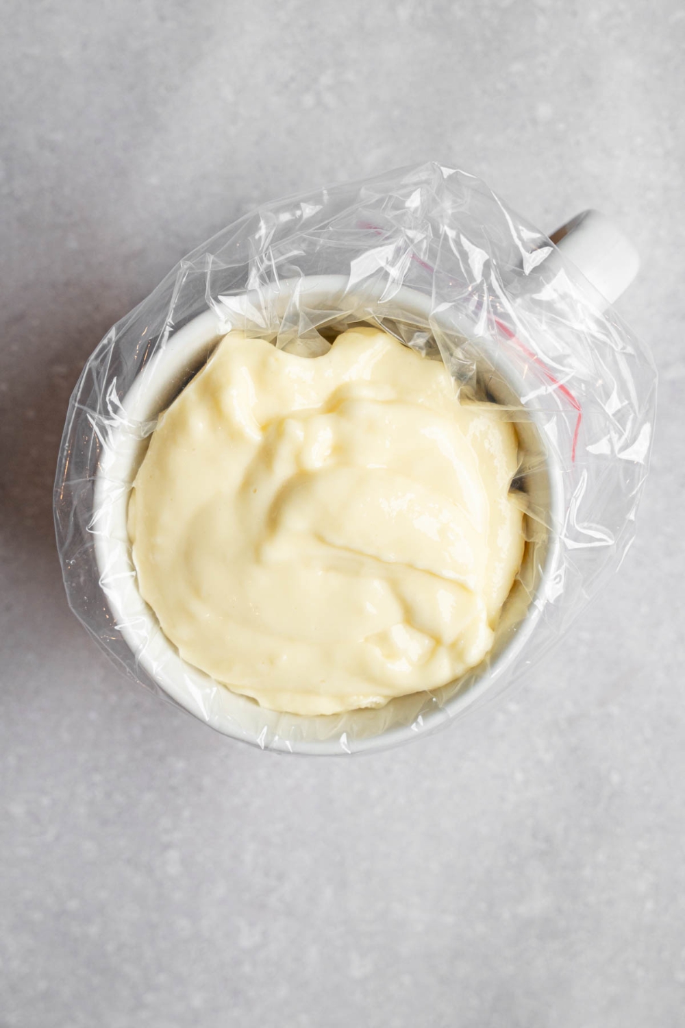 A pipette bag inserted into a mug. The bag is filled with pancake batter.