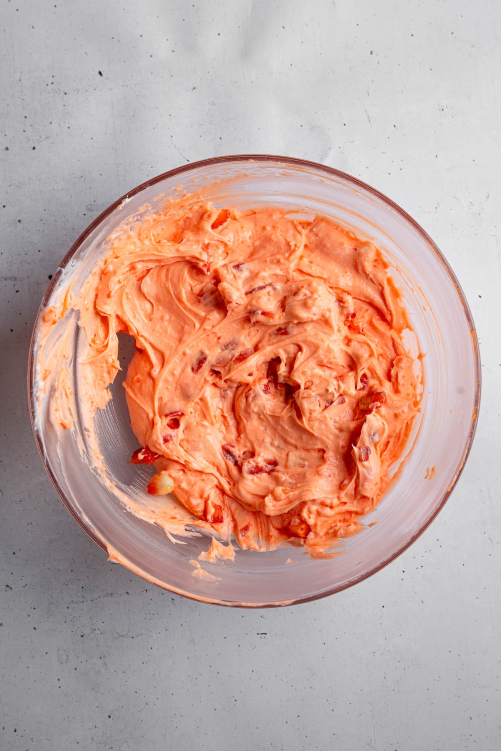 A glass bowl with whipped strawberry fluff salad. The bowl is on a white counter.