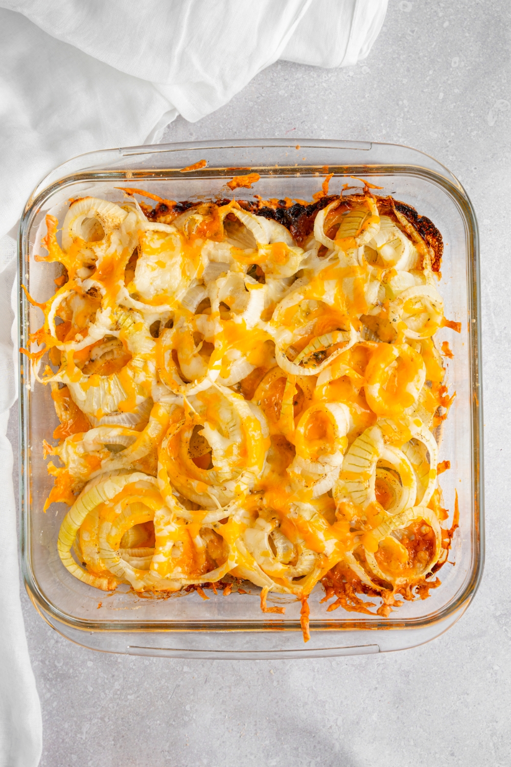 A square glass baking dish with cooked Tennessee onions. The dish is on a white counter with a white cloth napkin.