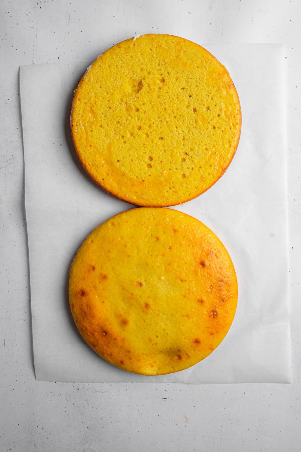 Two mango cake layers on a slice of parchment paper.