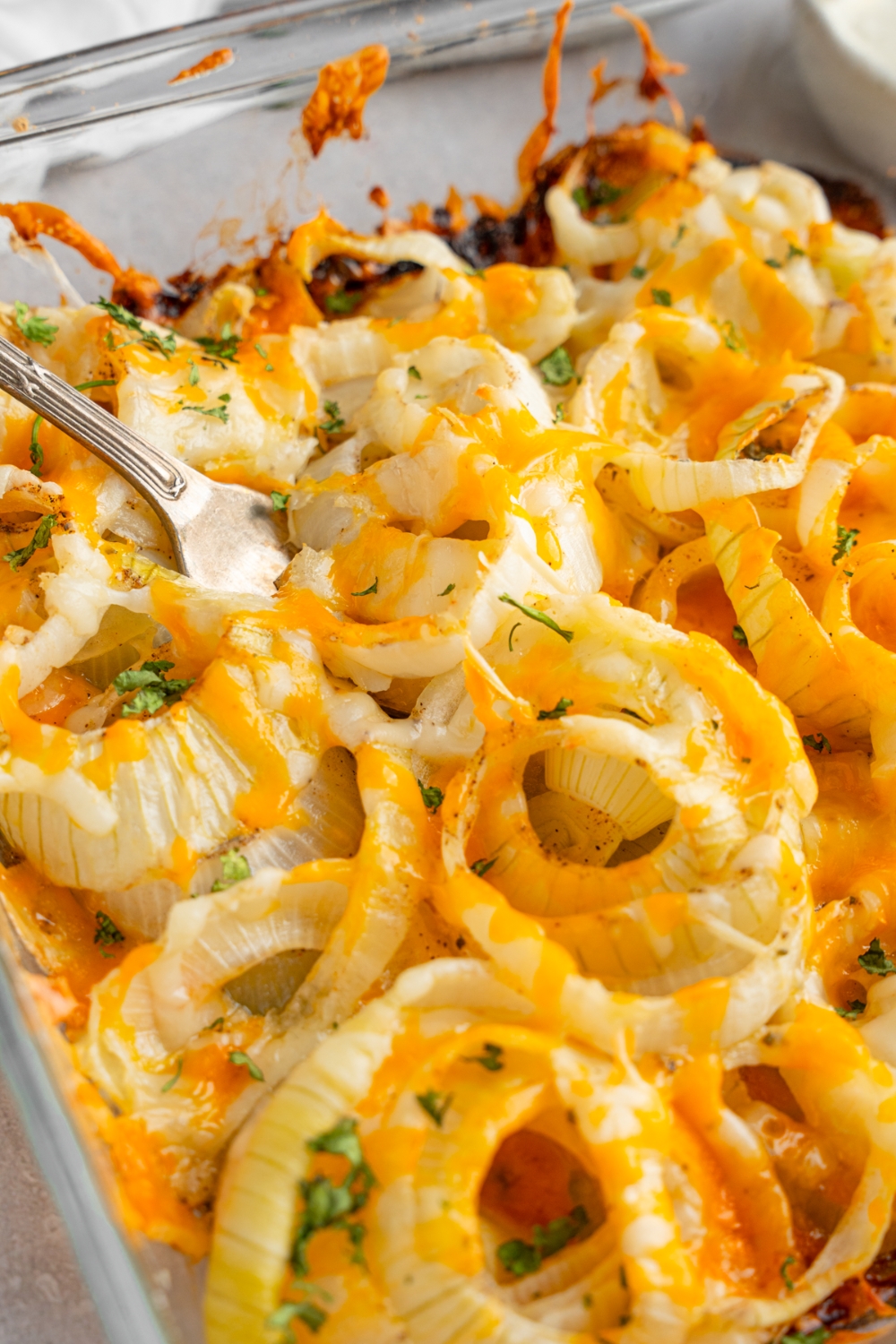 Tennessee onions in a glass baking dish garnished with fresh parsley. There is a fork in the onions.
