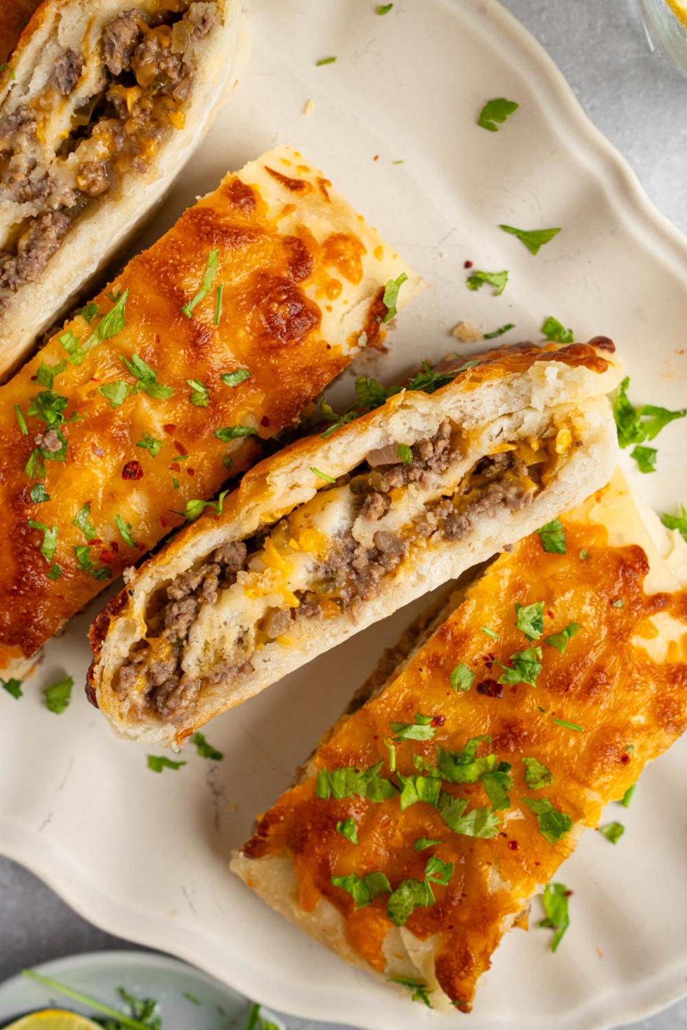 Slices of garbage bread served on a white platter garnished with chopped parsley. Some slices are on their side. The platter is on a white counter.