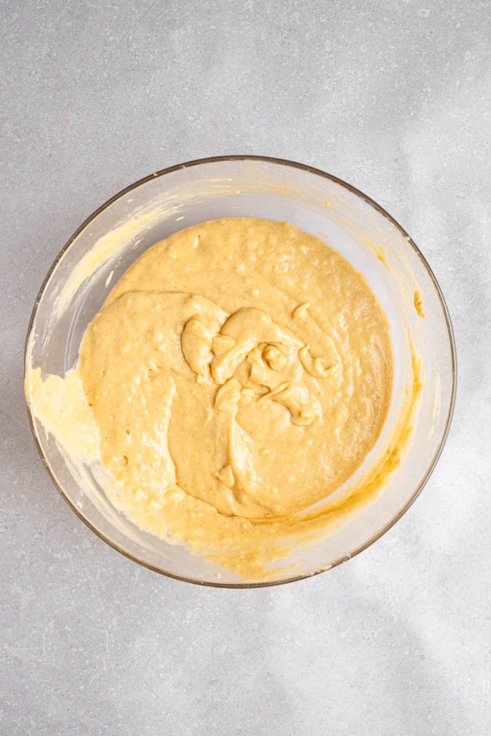A glass bowl with Amish applesauce batter. The bowl is on a white counter.